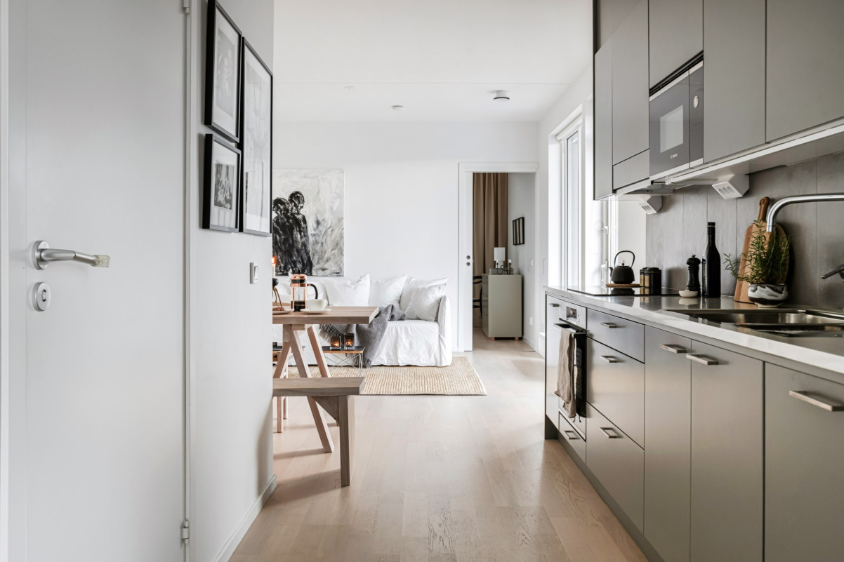 Vackert modernt kök från vedum med ljus stenskiva som smälter fint över till vardagsrummet. Redaregatan 34