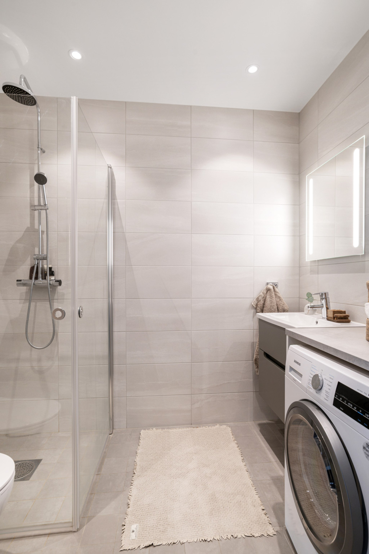 Modernt helkaklat badrum med dusch och tvätt torktumlare från siemens. Redaregatan 34