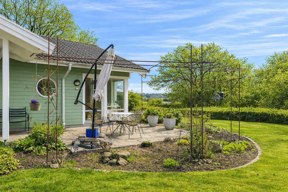 Stenlagd uteplats på framsidan. AI redigerad bild på grönska. Avvikelse på omgivande grönska. Medeltidsvägen 13