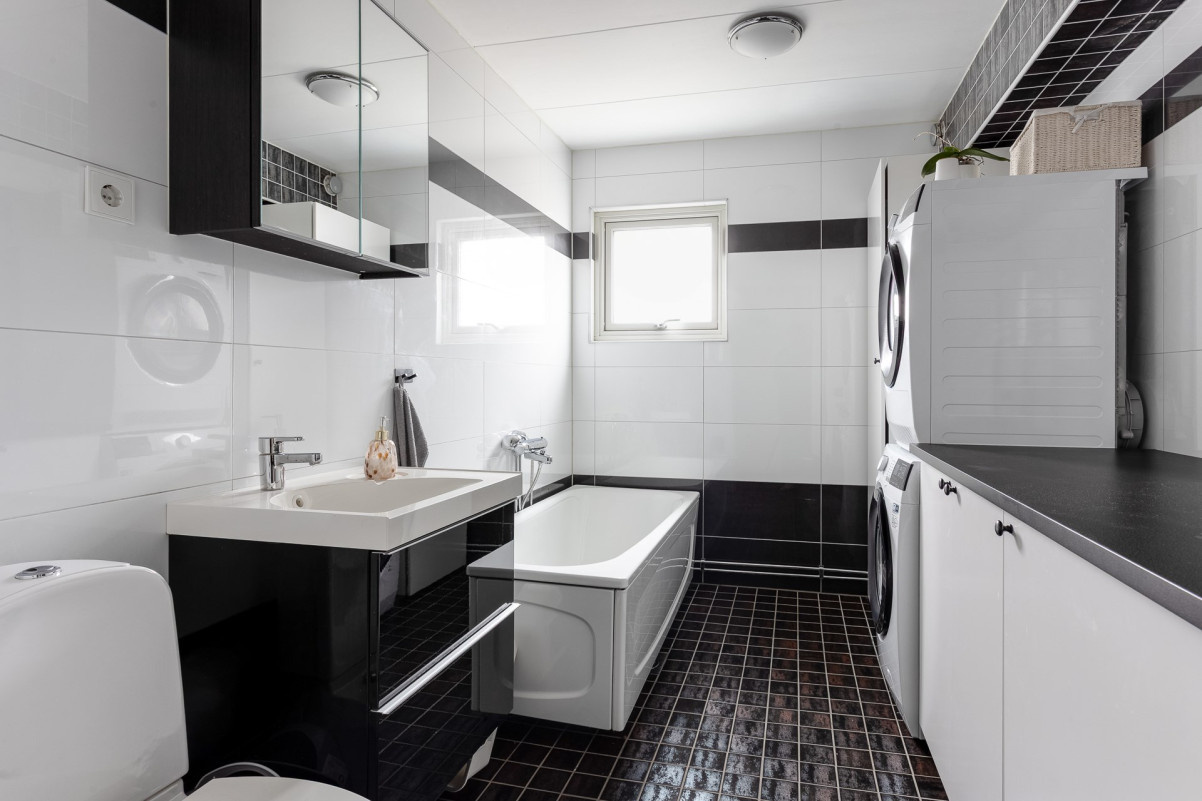 Helkaklat badrum på nedre plan med tvättmaskin och torktumlare Tellusgatan 25A